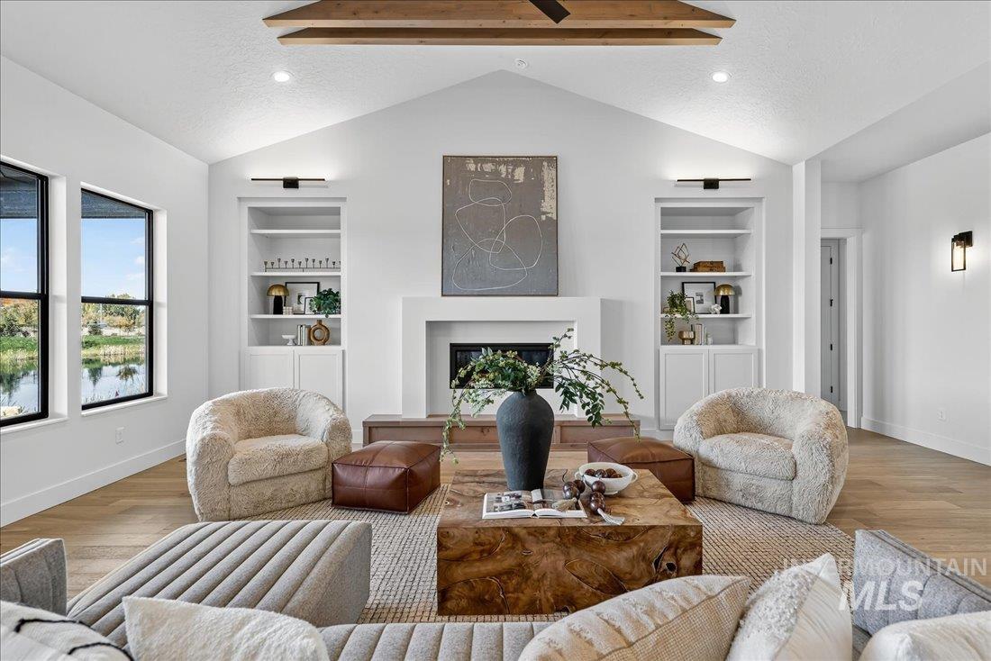 Living room with built in features, vaulted ceiling, a fireplace, wood finished floors, and a textured ceiling