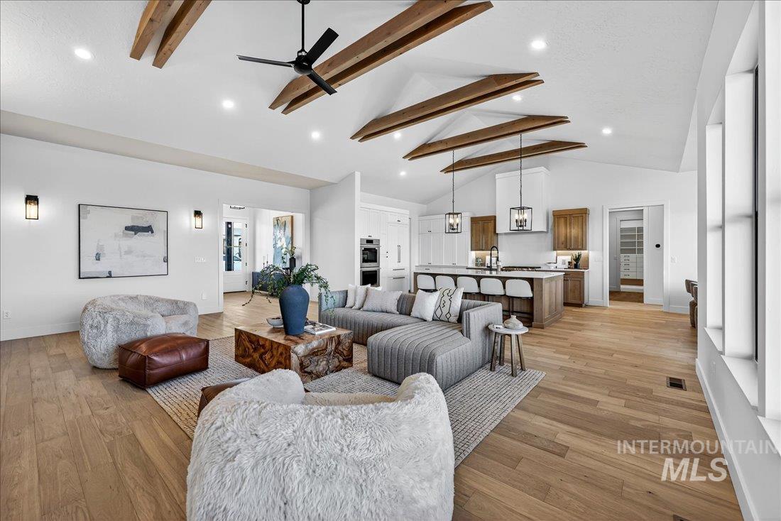 Living room featuring beam ceiling, high vaulted ceiling, a ceiling fan, light wood-style floors, and recessed lighting