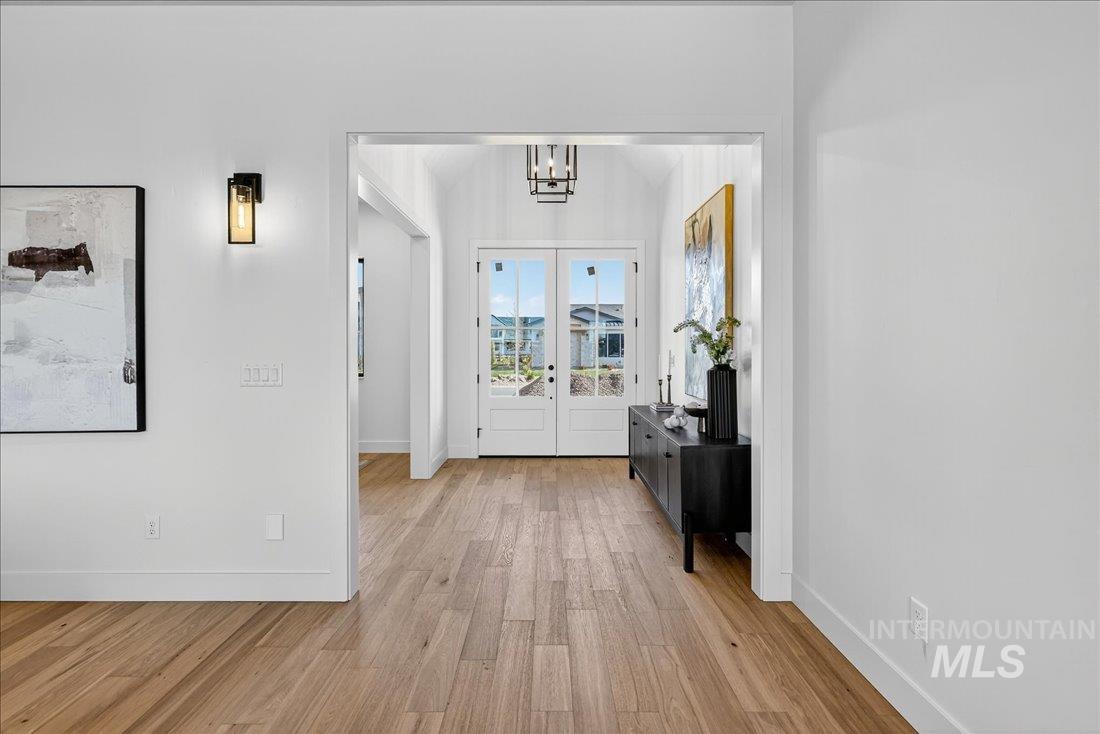 Entrance foyer with light wood-style floors, french doors, and a chandelier