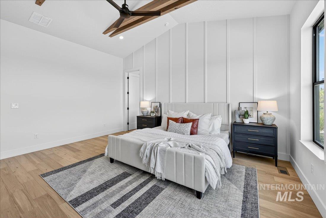 Bedroom featuring a ceiling fan, light wood finished floors, a decorative wall, and high vaulted ceiling