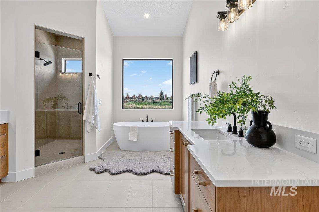 Full bath with vanity, a shower stall, a soaking tub, and light tile patterned flooring