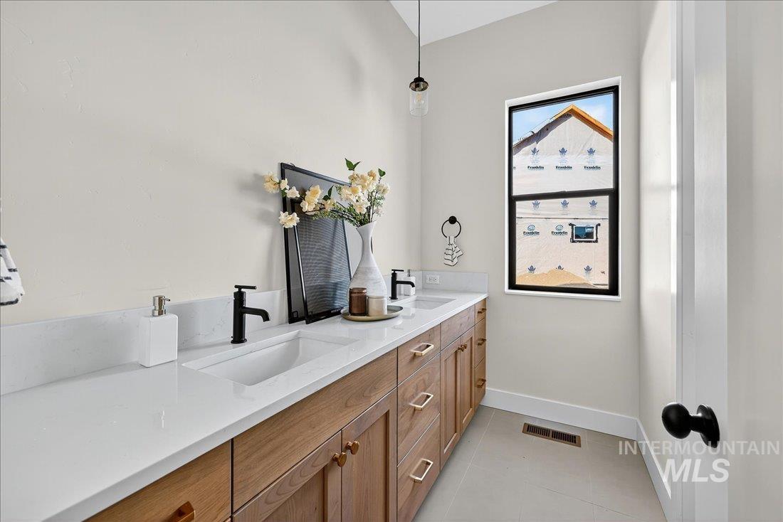 Bathroom with double vanity and light tile patterned floors