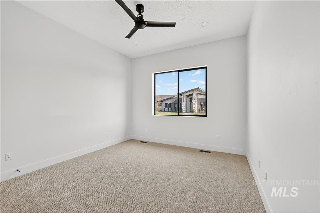 Unfurnished room featuring light carpet, ceiling fan, and a textured ceiling