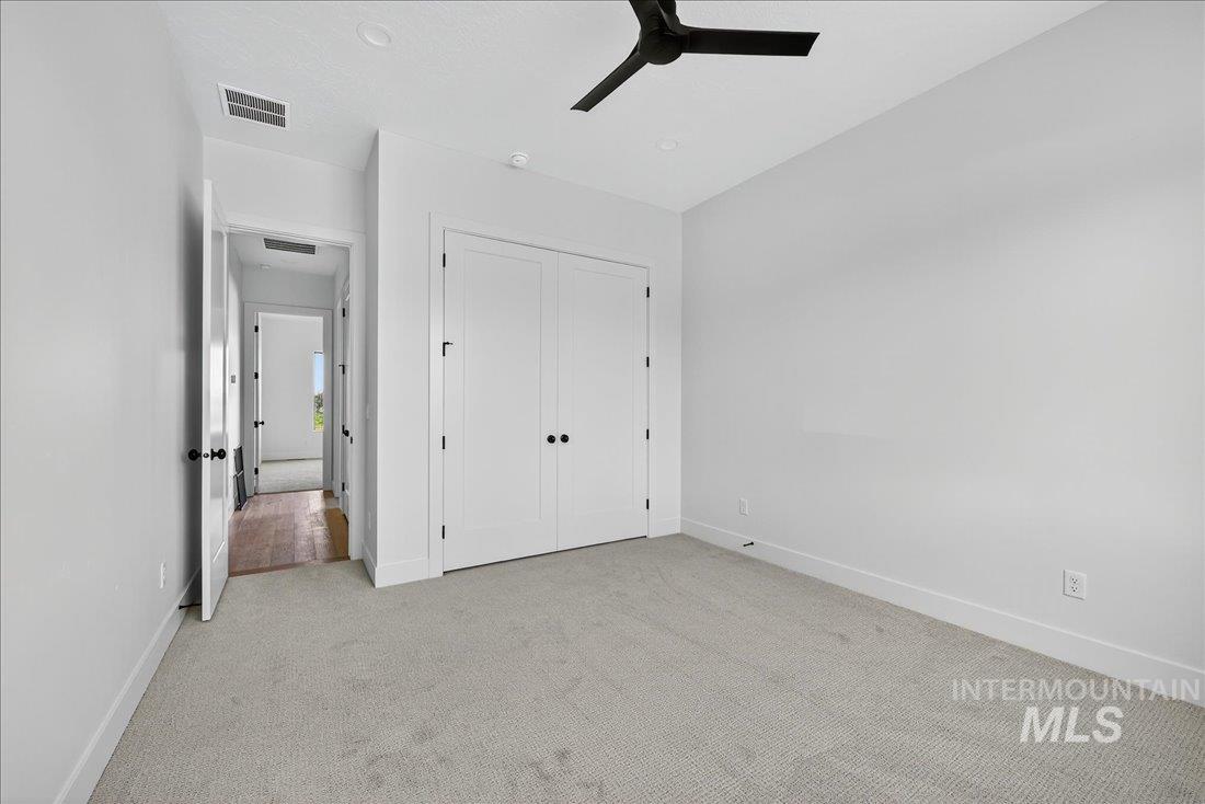 Unfurnished bedroom with light colored carpet, a ceiling fan, and a closet