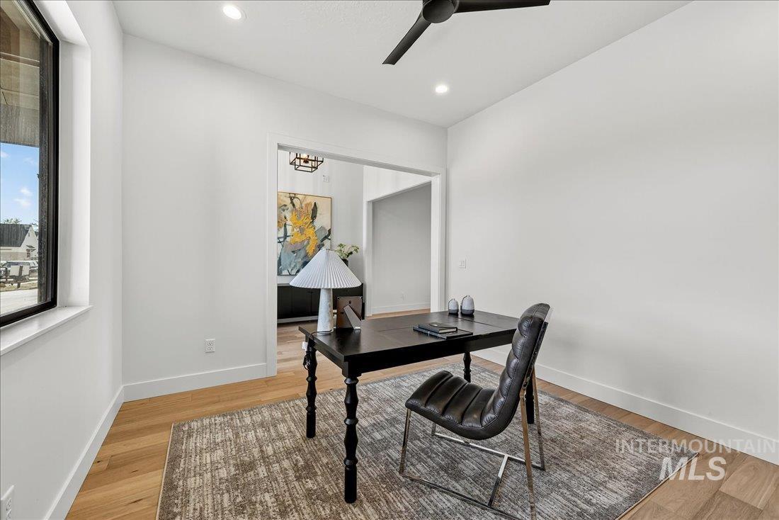Office space featuring light wood-style floors, recessed lighting, ceiling fan, and a chandelier