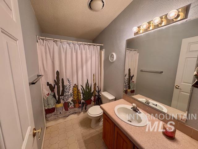 Full bath with a textured ceiling, vanity, a textured wall, and shower / tub combo