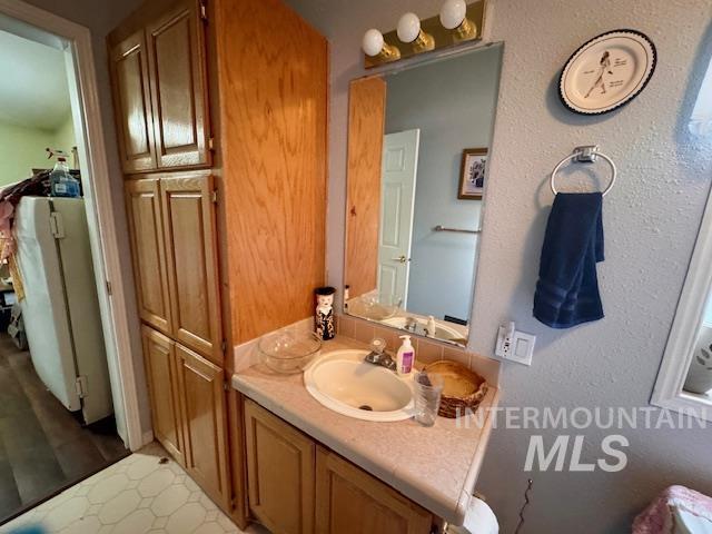 Bathroom featuring vanity and a textured wall