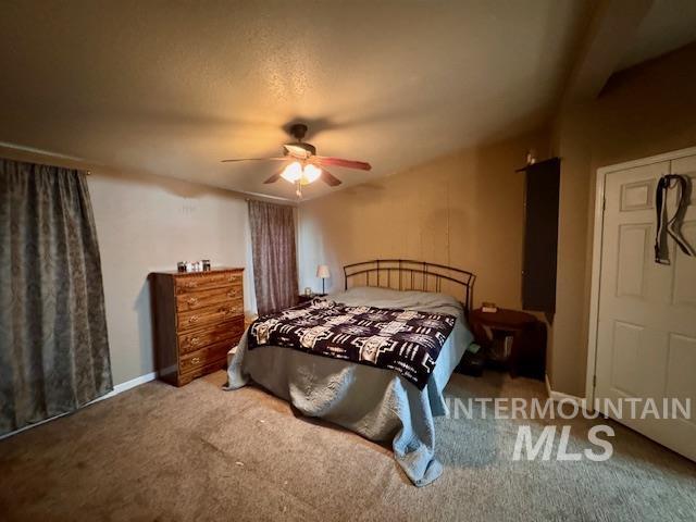 Carpeted bedroom featuring a ceiling fan and a textured ceiling
