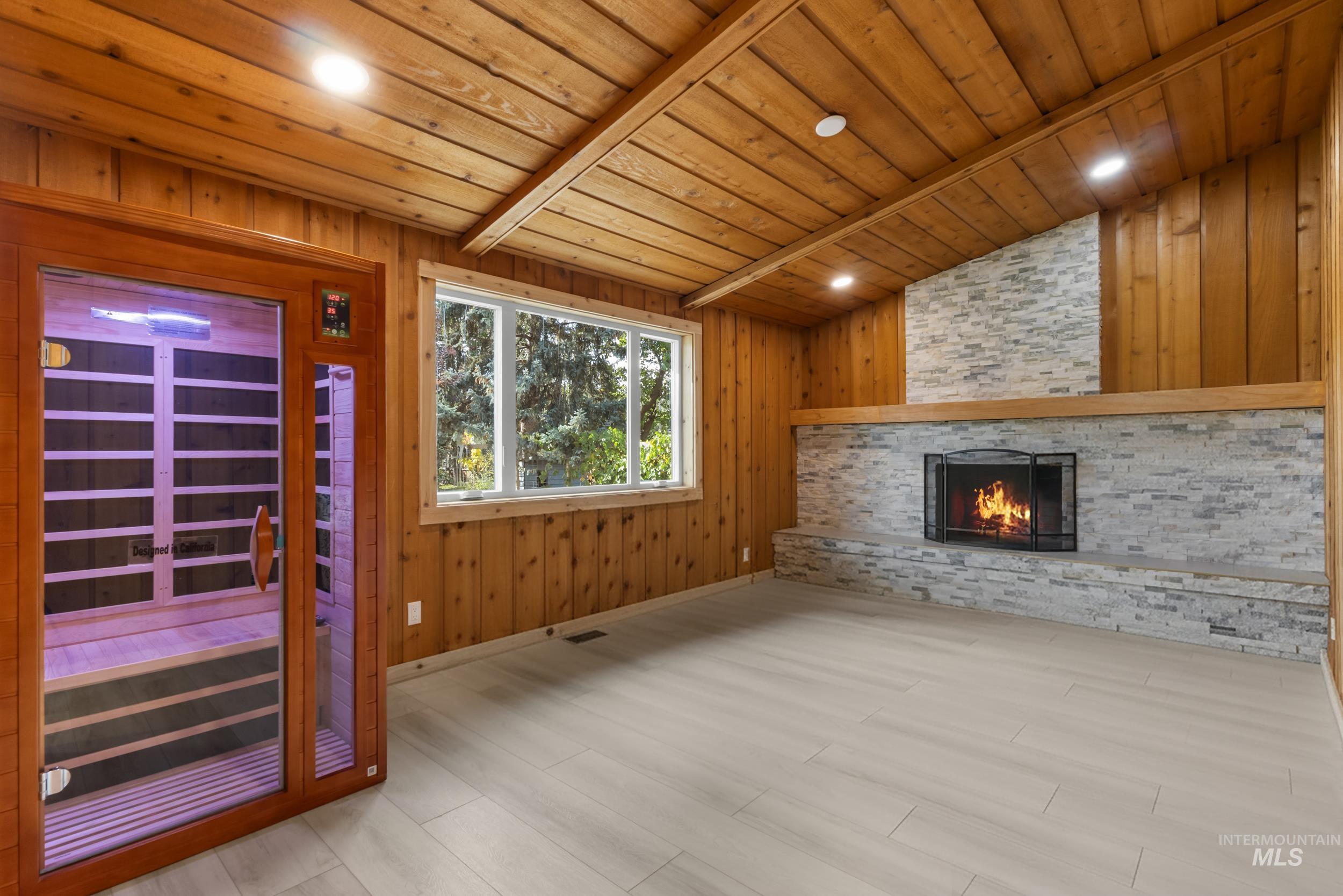 Unfurnished living room featuring recessed lighting, wood walls, a stone fireplace, wood finished floors, and wooden ceiling