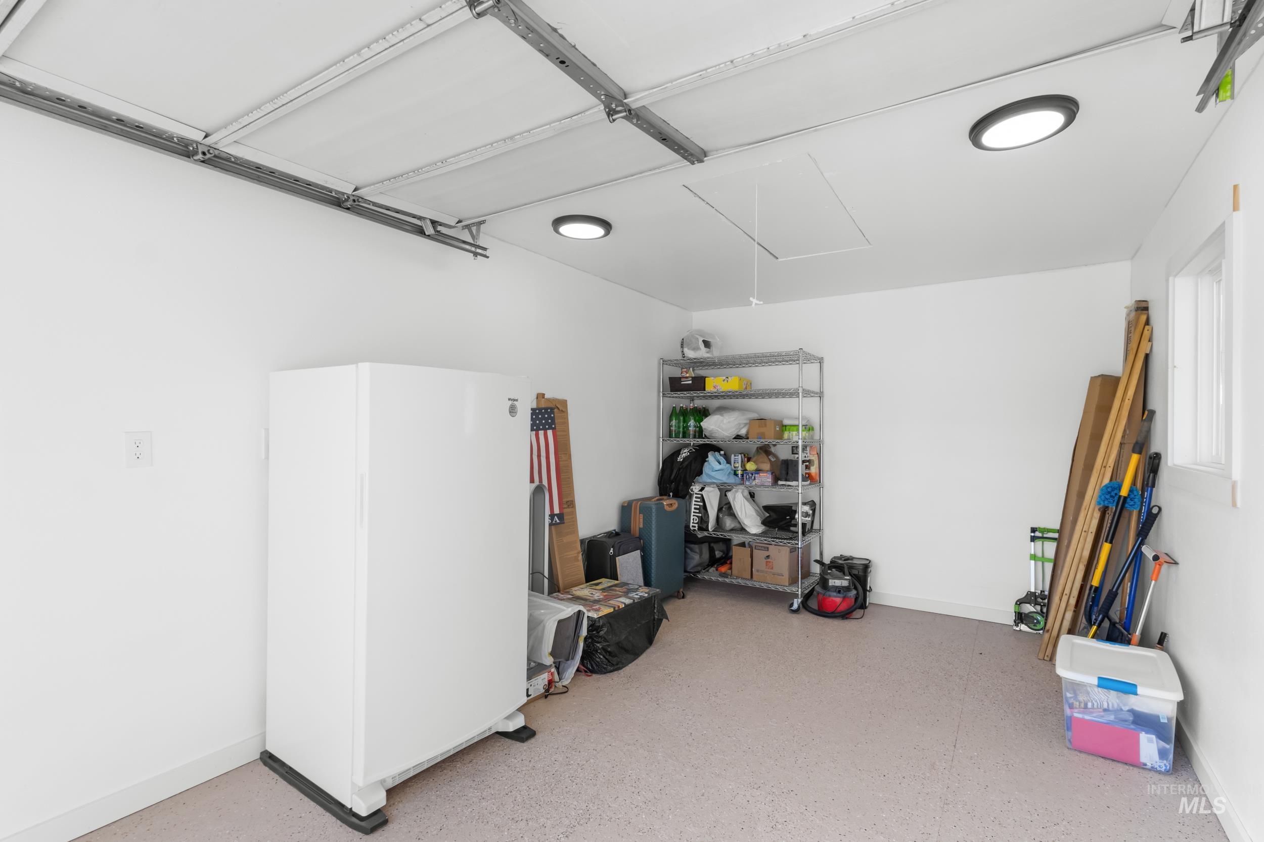 Garage featuring baseboards and freestanding refrigerator
