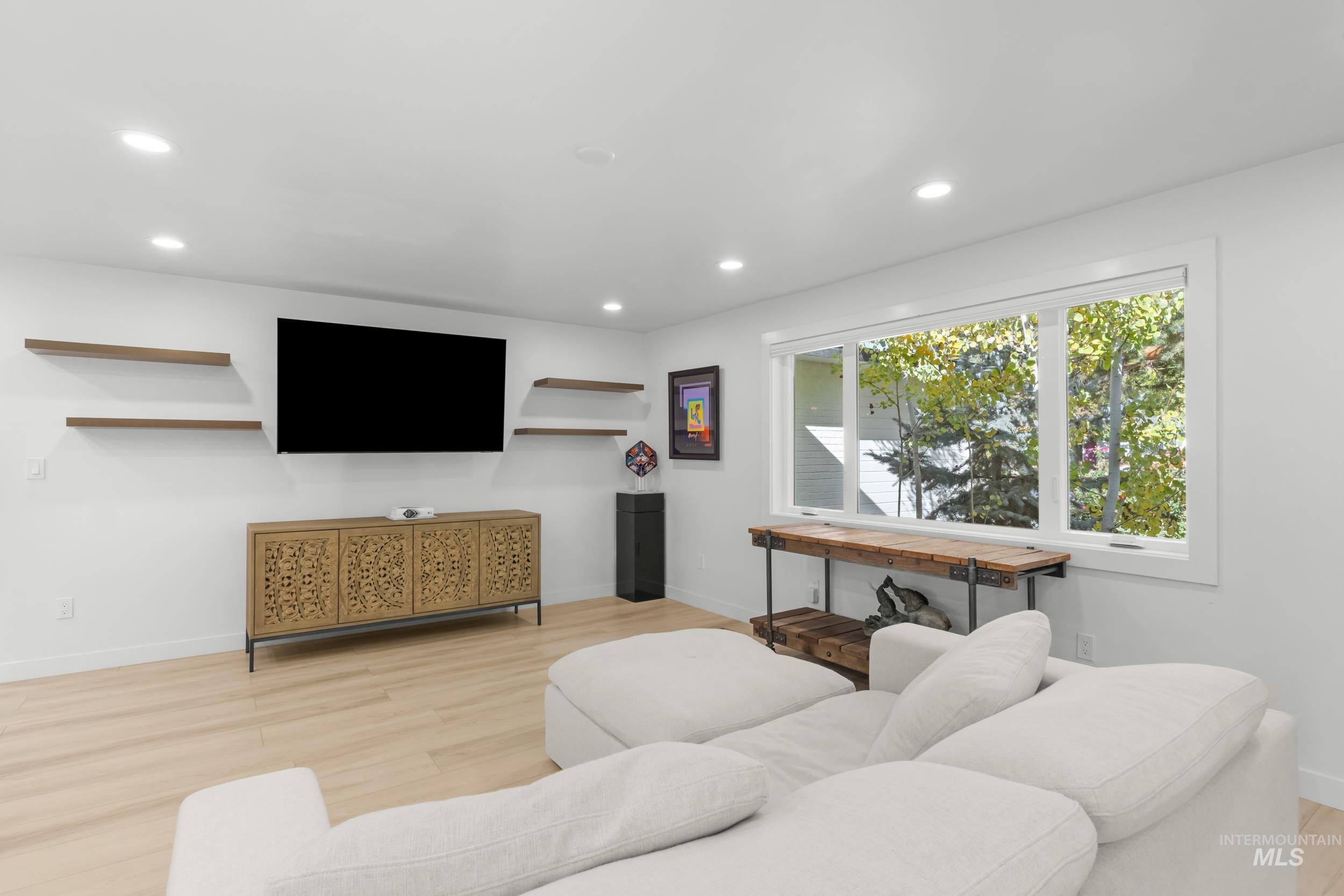 Living area with light wood finished floors and recessed lighting