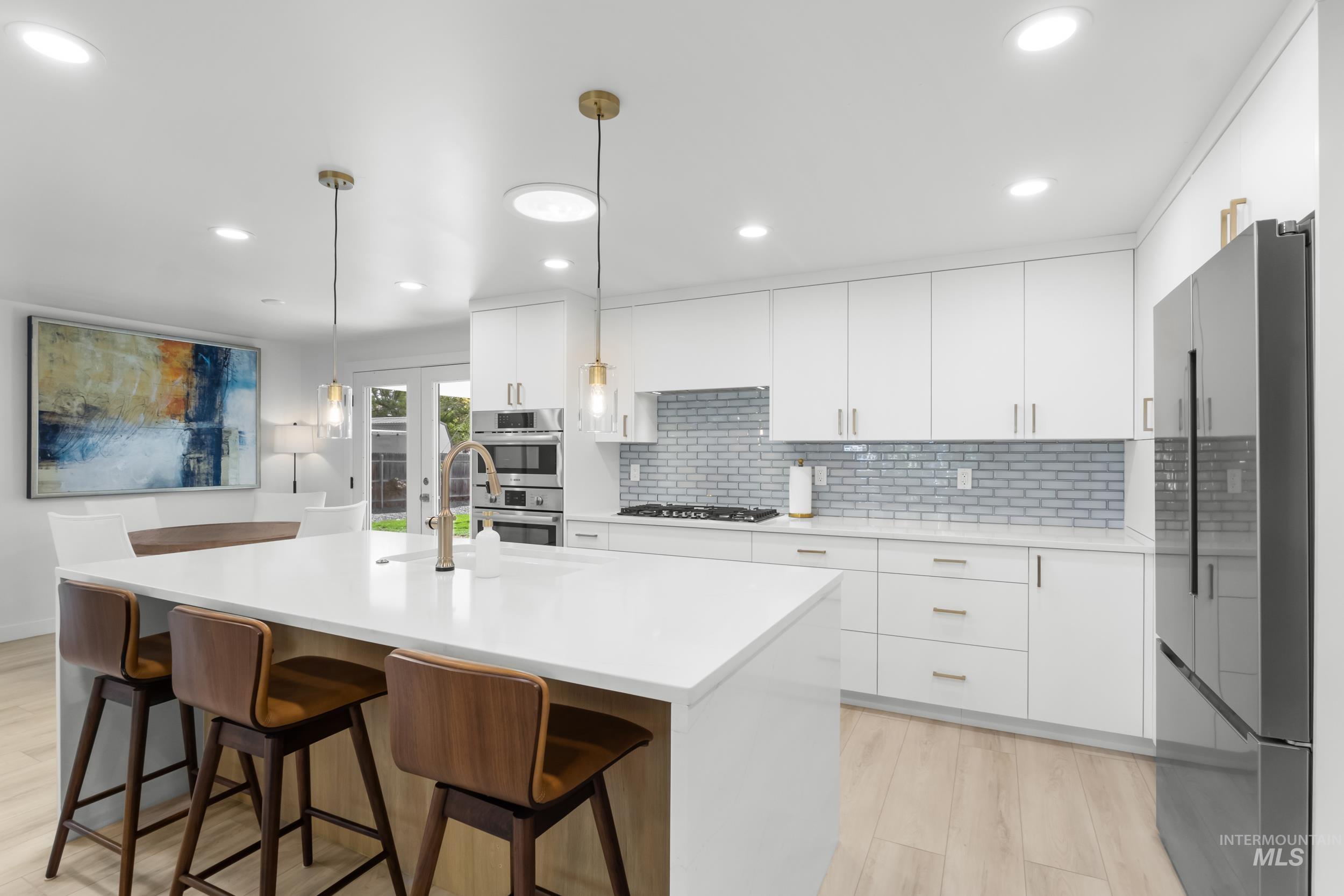 Kitchen with modern cabinets, white cabinetry, tasteful backsplash, a kitchen bar, and recessed lighting