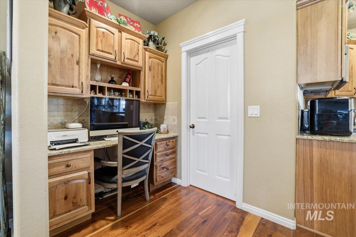Office space with built in desk and dark wood-style floors