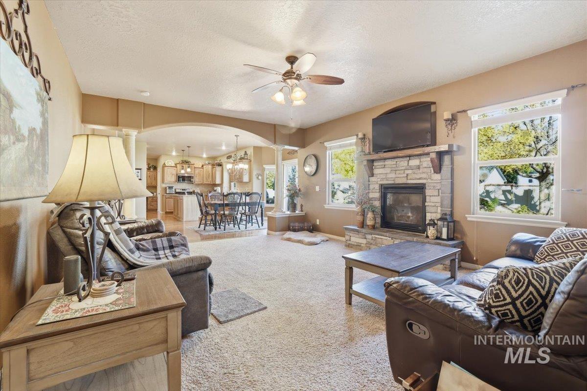 Living area featuring arched walkways, a fireplace, carpet, a textured ceiling, and plenty of natural light