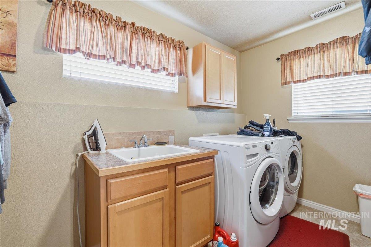 Washroom with a textured wall, washing machine and clothes dryer, a textured ceiling, and cabinet space