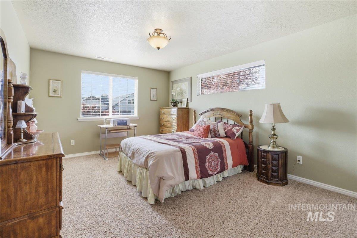 Bedroom featuring light colored carpet and a textured ceiling