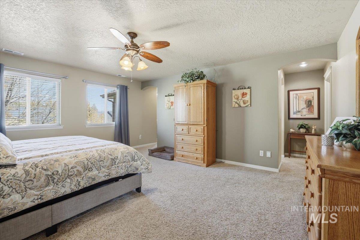 Bedroom with light carpet, a textured ceiling, and a ceiling fan