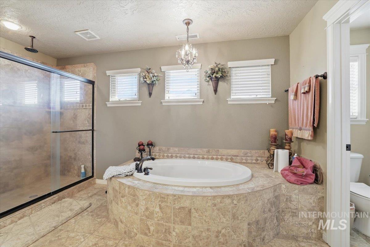 Full bathroom featuring a garden tub, a stall shower, a textured ceiling, and light tile patterned floors