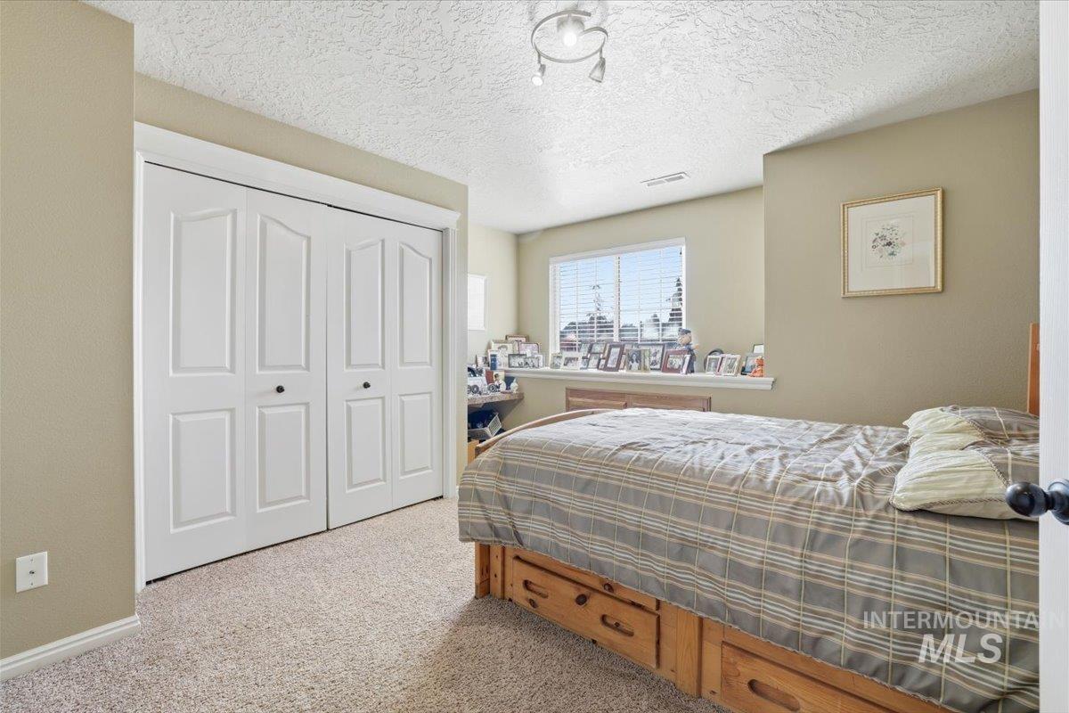 Bedroom featuring light colored carpet, a closet, and a textured ceiling