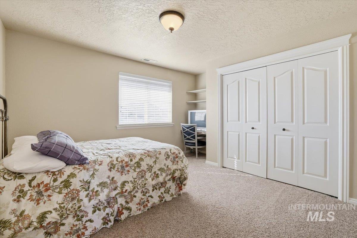 Carpeted bedroom featuring a textured ceiling and a closet