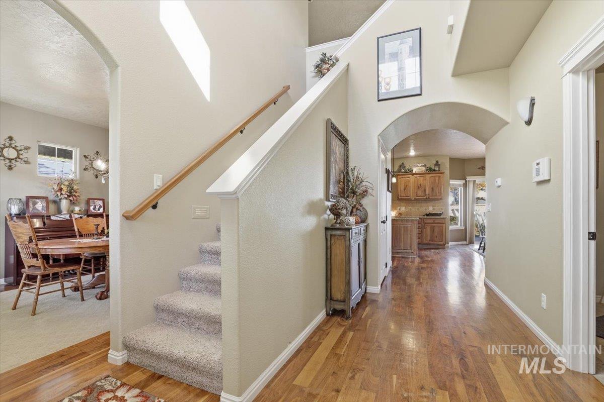 Hall with arched walkways, dark wood finished floors, a high ceiling, stairway, and a textured ceiling
