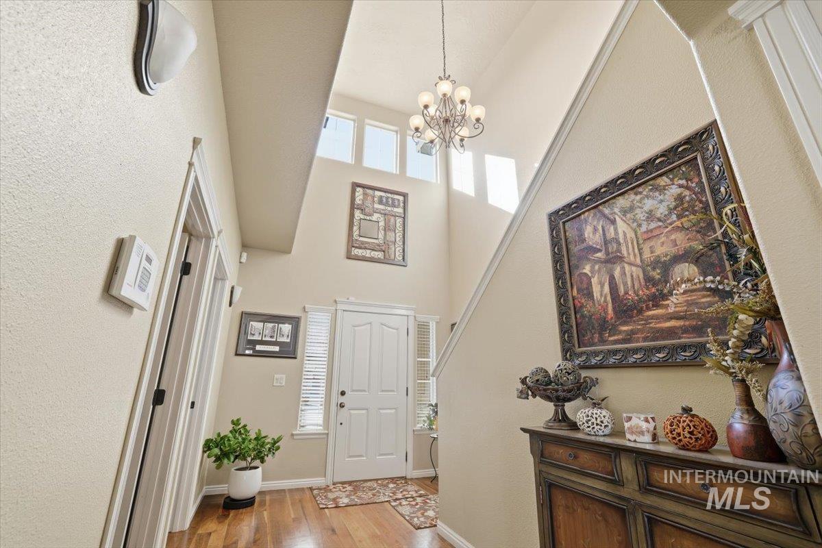 Foyer featuring light wood-style floors, plenty of natural light, a towering ceiling, and a chandelier