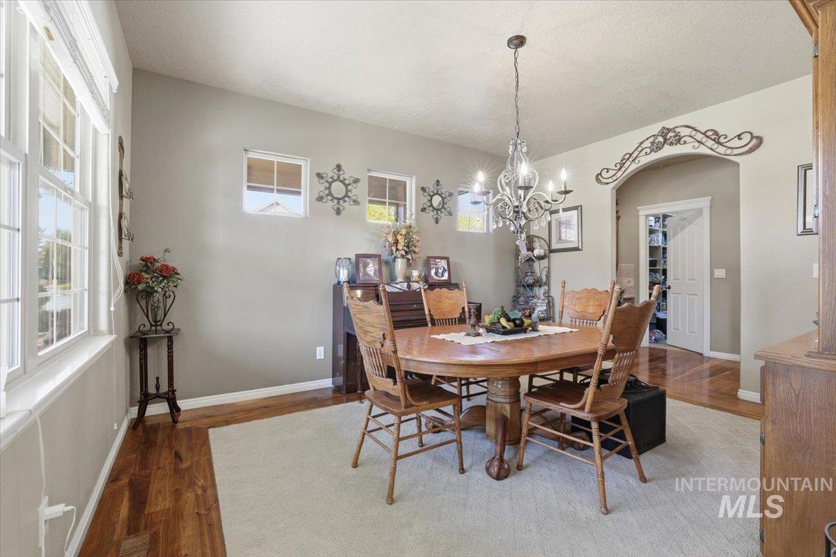 Dining area featuring wood finished floors, arched walkways, plenty of natural light, a chandelier, and a textured ceiling