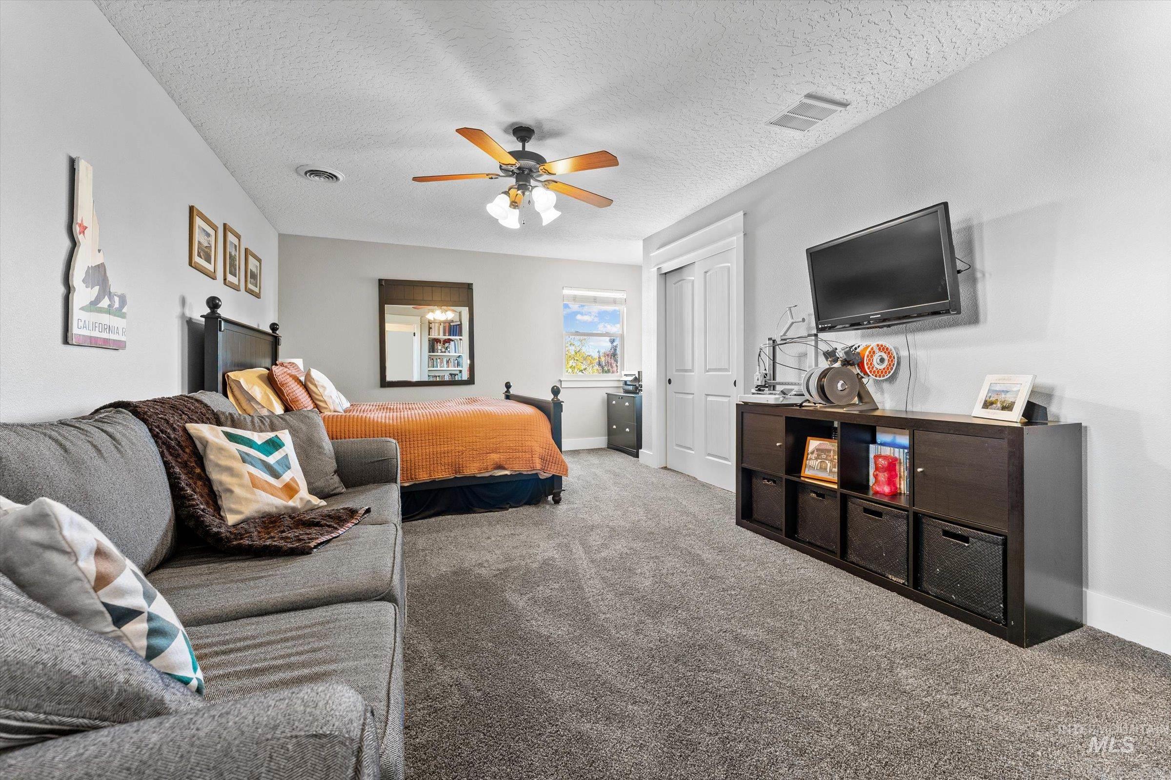 Bedroom with carpet floors, a closet, a textured ceiling, and ceiling fan