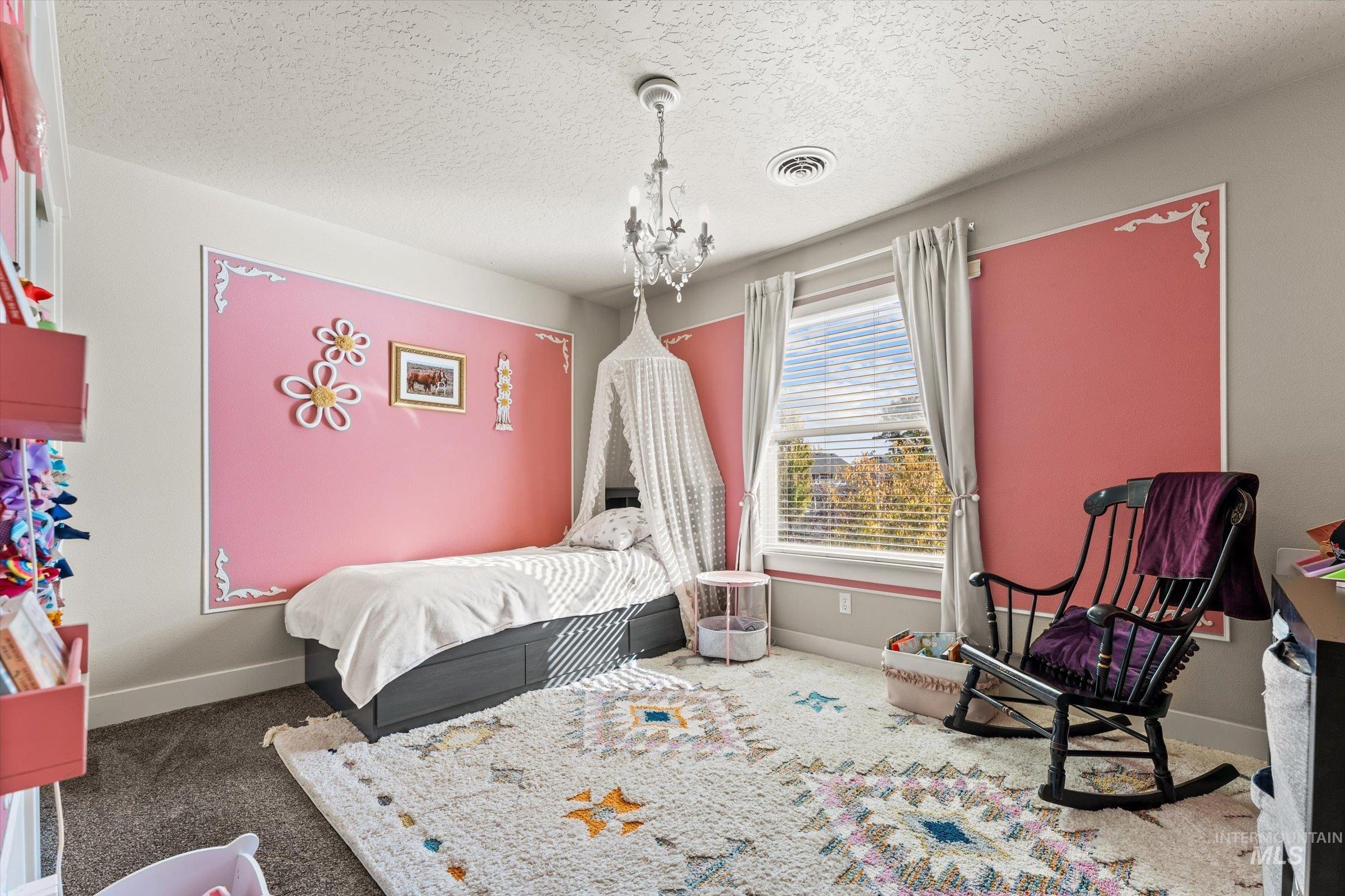 Bedroom with a textured ceiling, carpet, and a chandelier