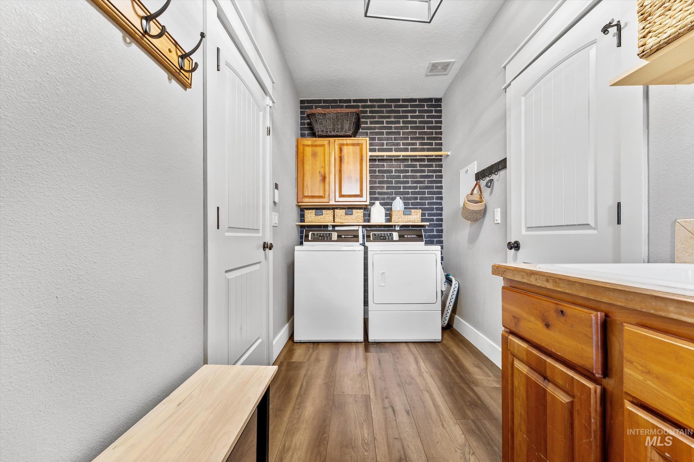 Laundry room with cabinet space, dark wood-style flooring, independent washer and dryer, and a textured ceiling