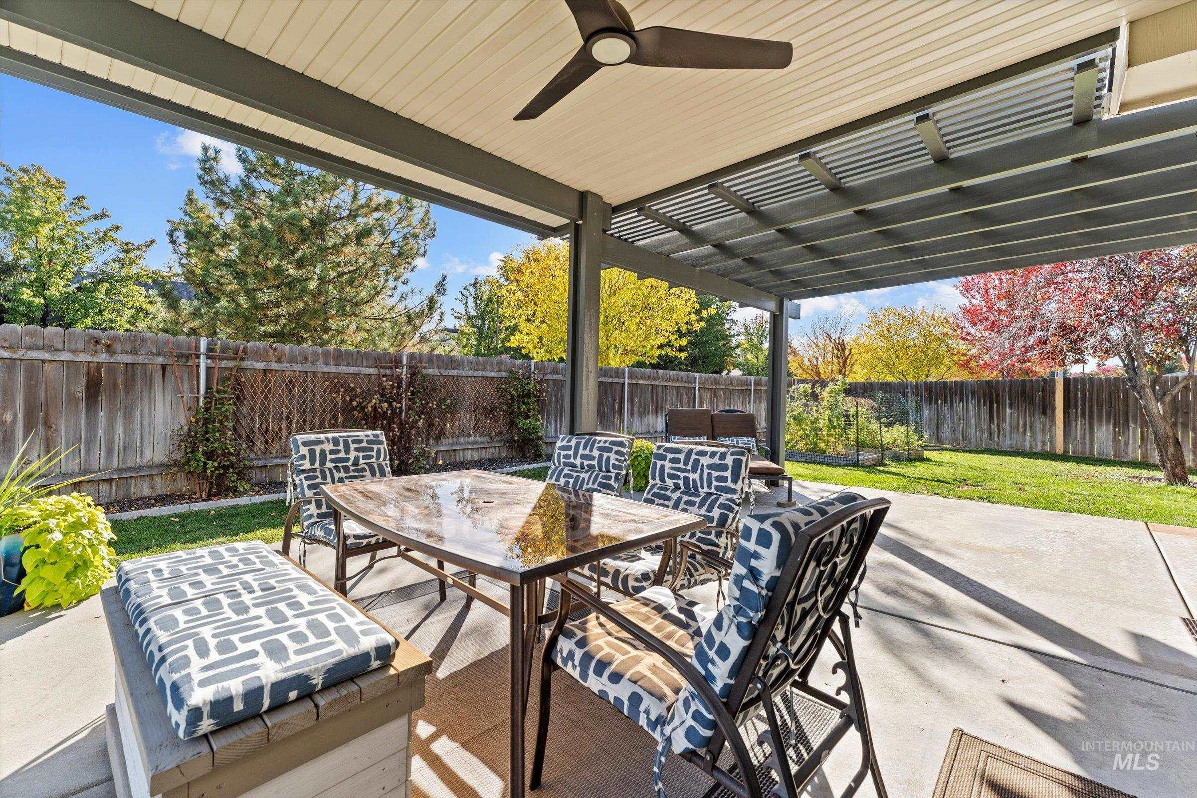 Fenced backyard with a ceiling fan, outdoor dining area, a patio, and a pergola