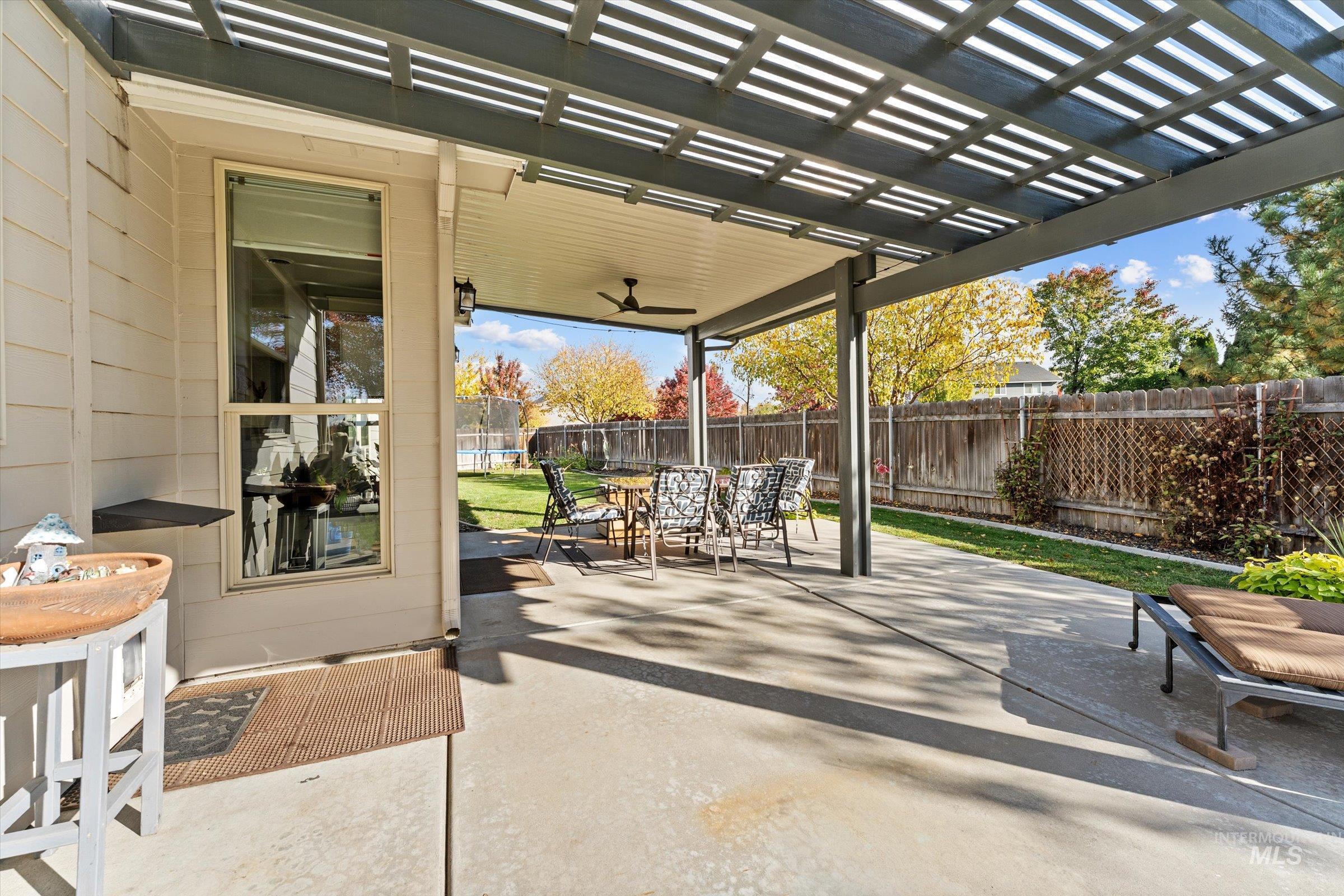 Fenced backyard with outdoor dining area, a patio area, a pergola, and ceiling fan