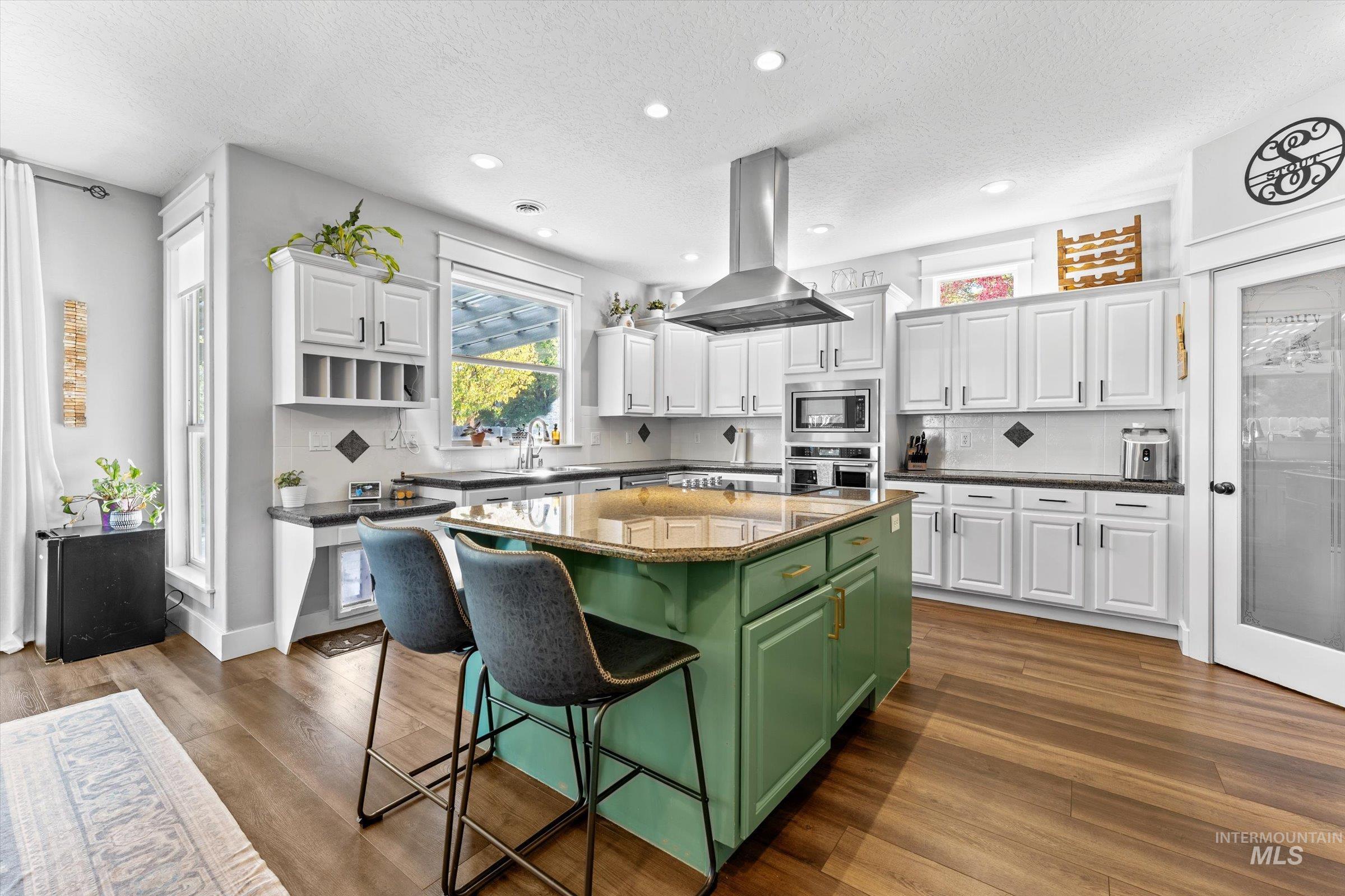 Kitchen featuring green cabinetry, white cabinets, a textured ceiling, tasteful backsplash, and recessed lighting