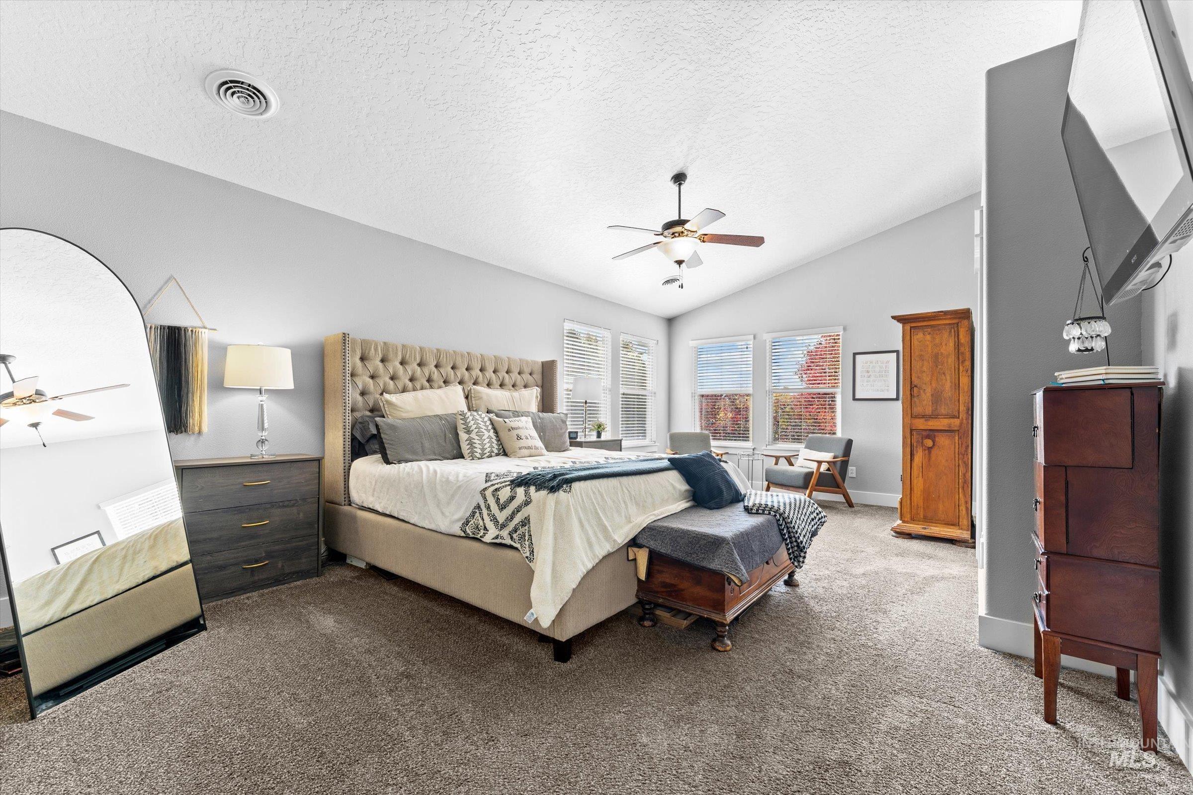 Carpeted bedroom with lofted ceiling, a textured ceiling, and ceiling fan