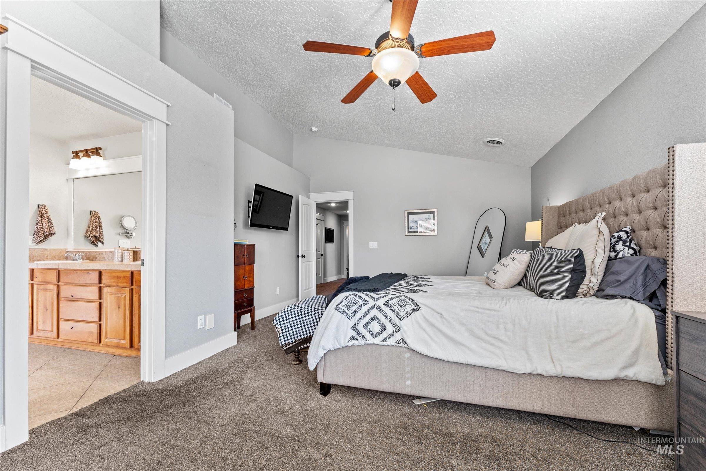 Bedroom featuring carpet flooring, a textured ceiling, lofted ceiling, tile patterned floors, and ceiling fan