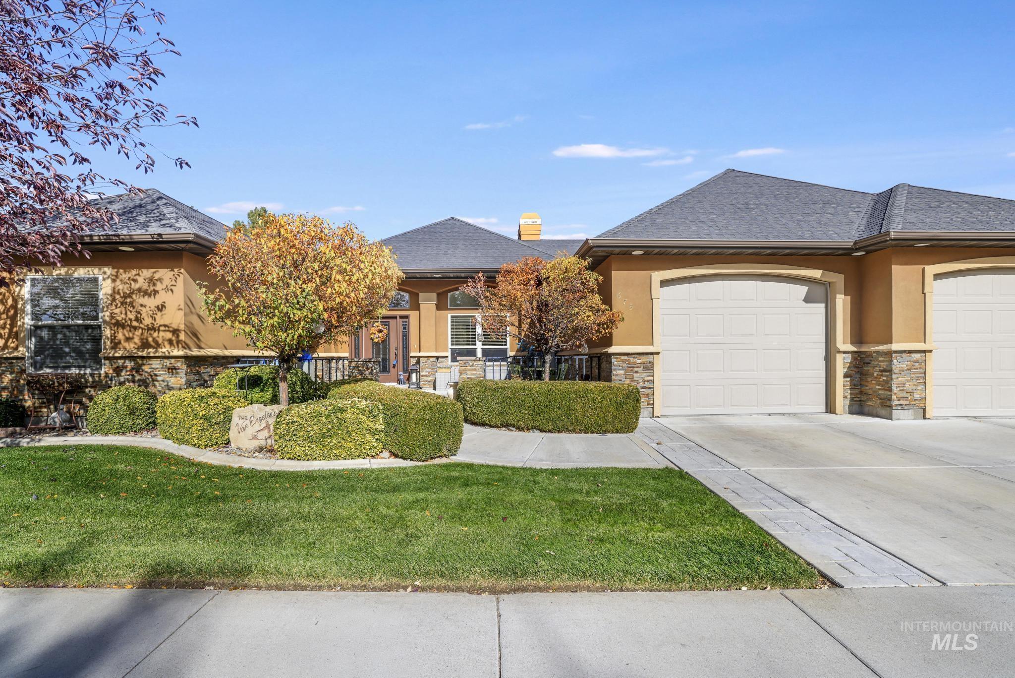 View of front of home with stucco siding, stone siding, an attached garage, and concrete driveway