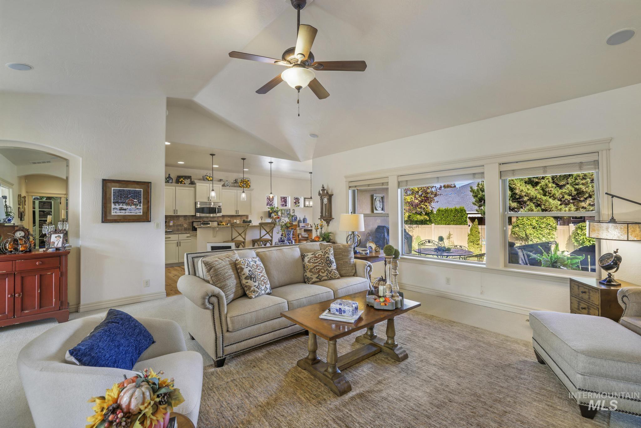 Living area featuring vaulted ceiling, arched walkways, and a ceiling fan