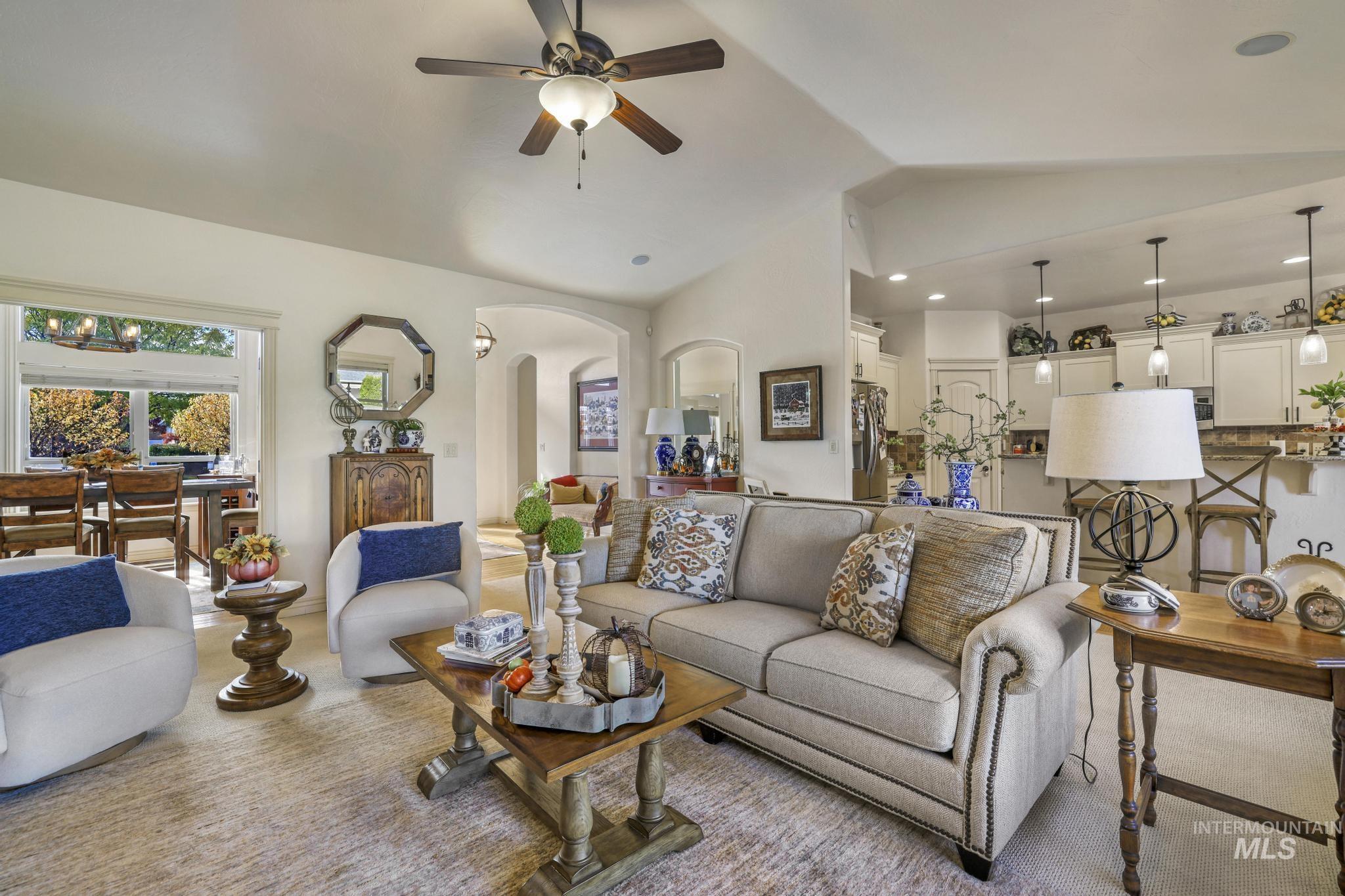 Living area with lofted ceiling, arched walkways, a ceiling fan, and recessed lighting