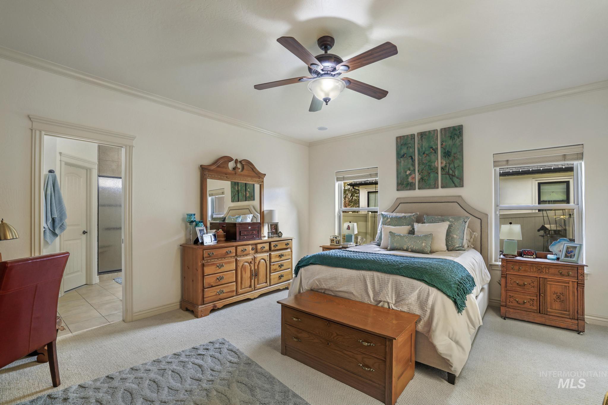 Carpeted bedroom with crown molding and a ceiling fan