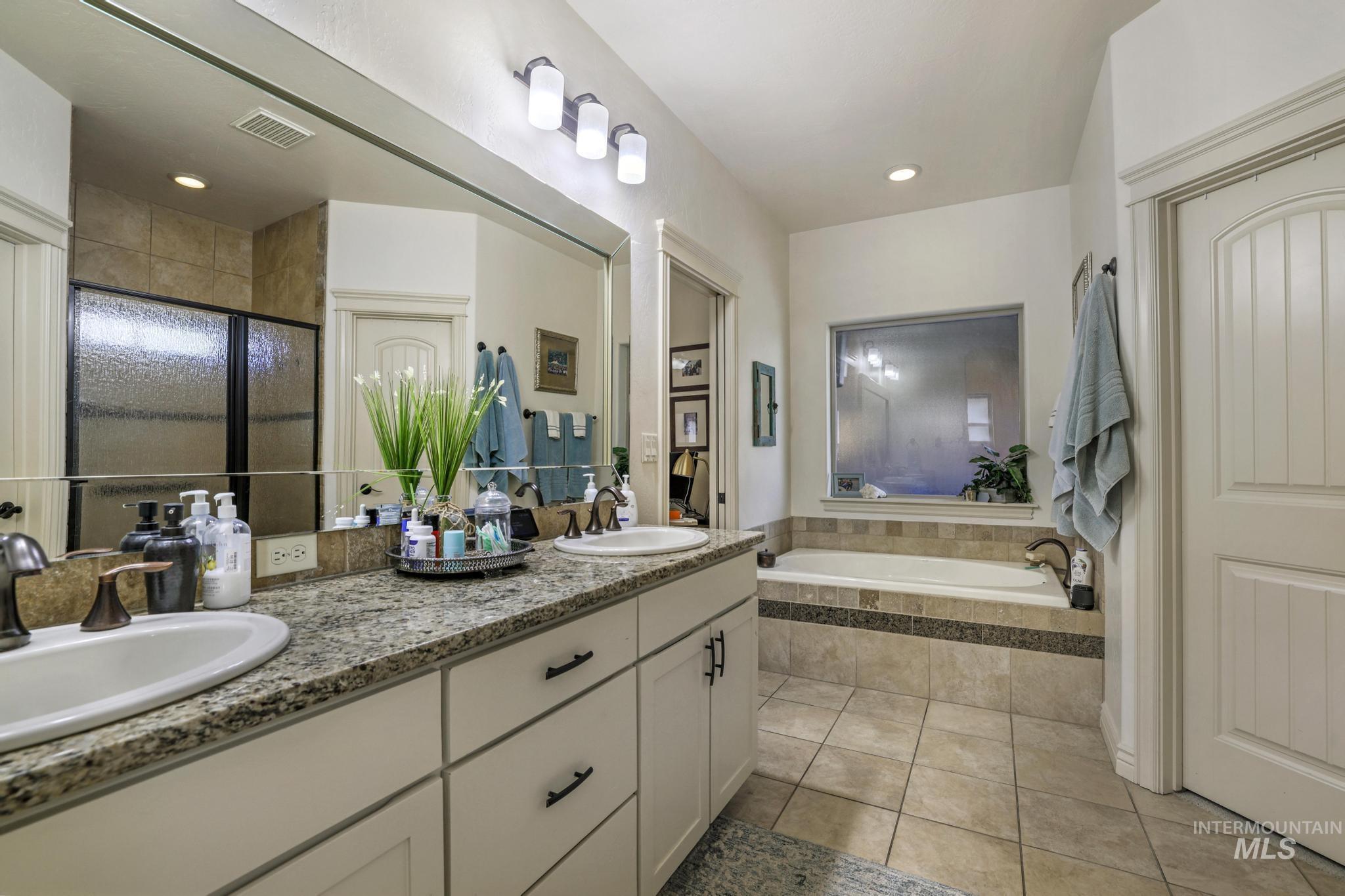 Full bathroom with double vanity, light tile patterned floors, a bath, a shower stall, and recessed lighting