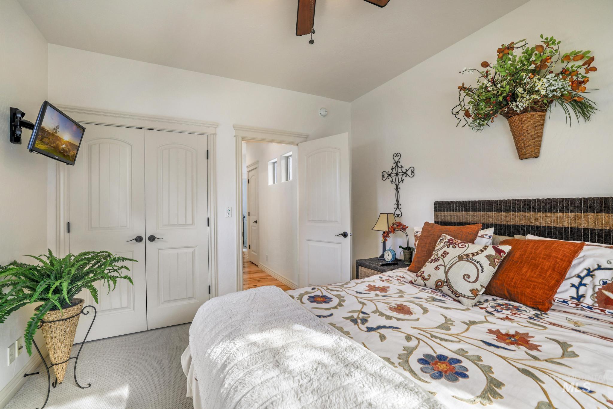 Bedroom with a closet, light colored carpet, and a ceiling fan