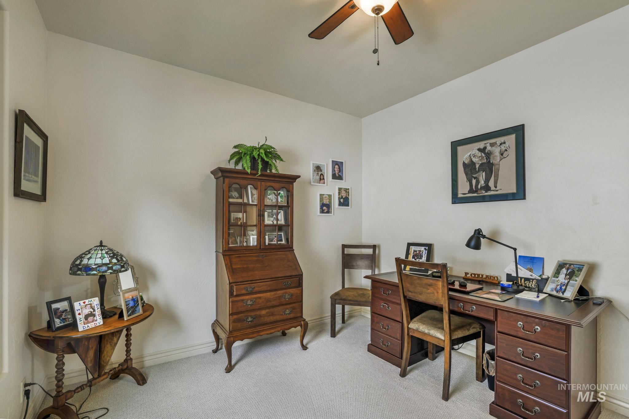 Home office with light colored carpet and a ceiling fan