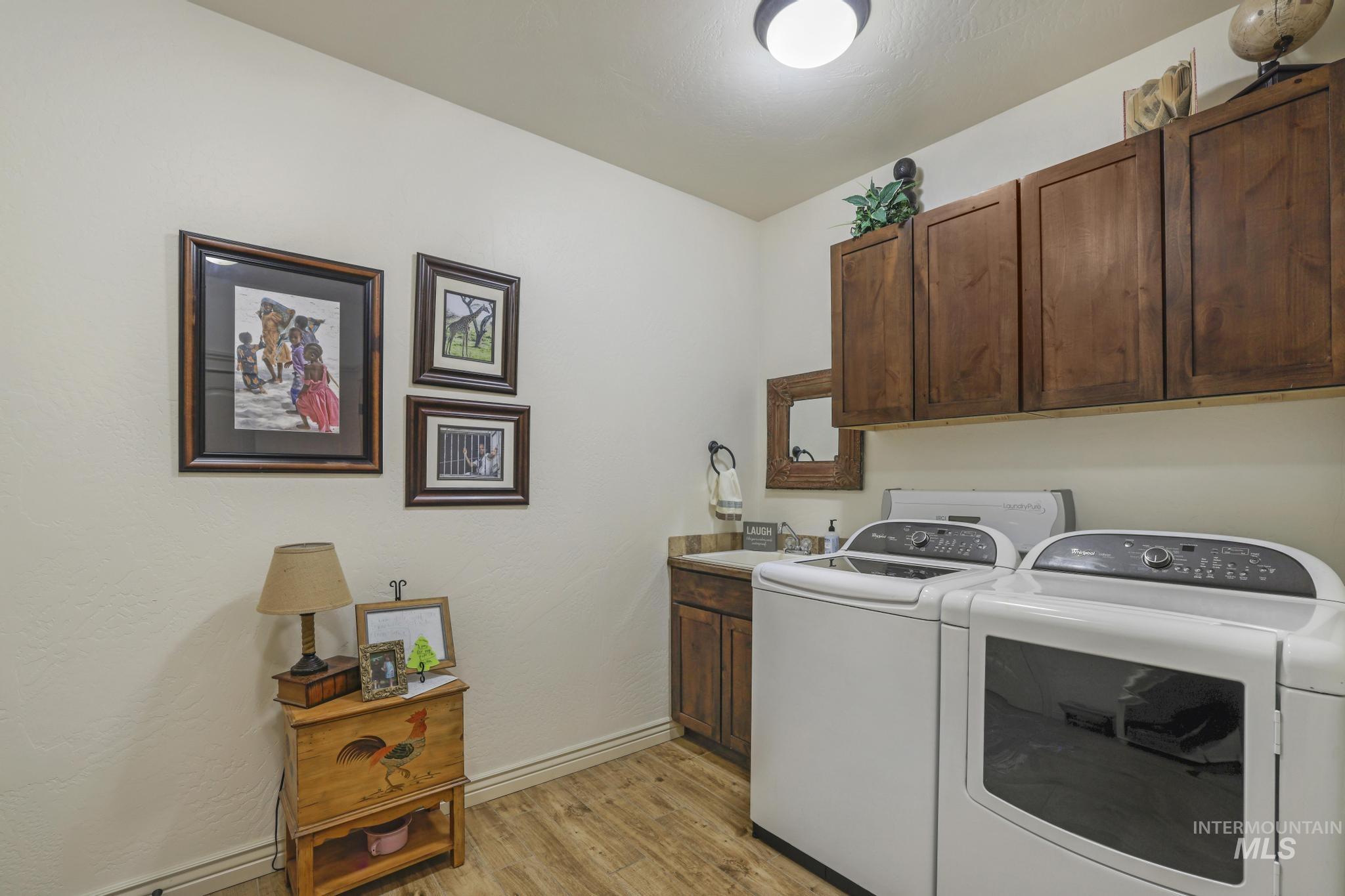 Laundry room featuring light wood-style floors, cabinet space, and washing machine and dryer