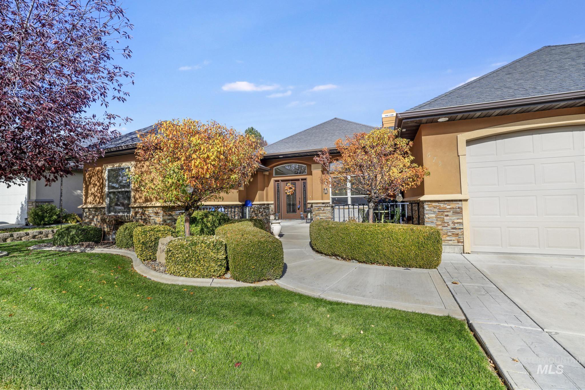 View of front of house with stone siding, a garage, a front lawn, and stucco siding