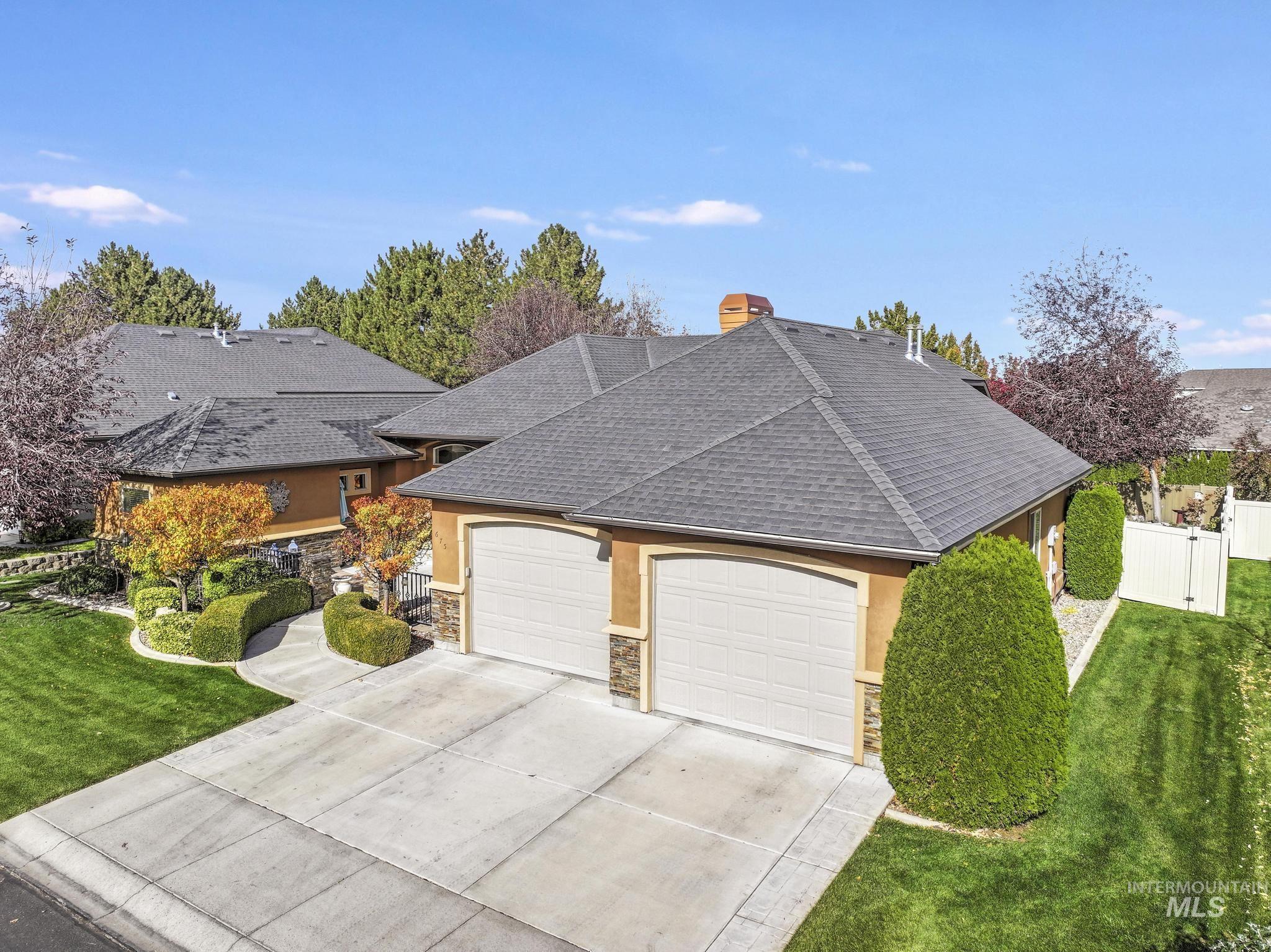 View of front of house featuring an attached garage, concrete driveway, stone siding, and stucco siding