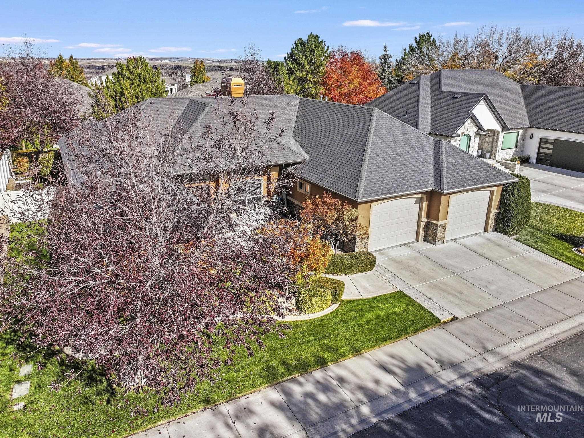 View of front of house with stone siding, a garage, concrete driveway, a front yard, and roof with shingles