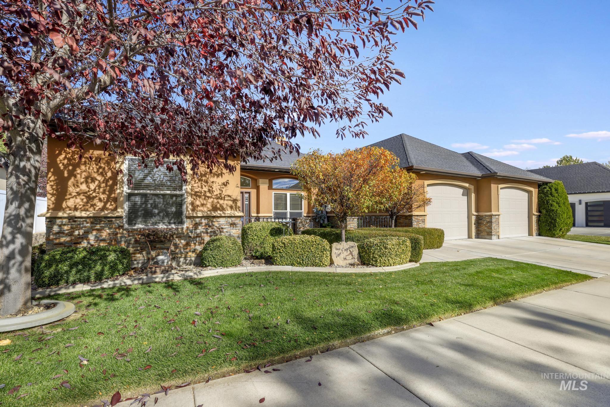 View of property hidden behind natural elements with stone siding, driveway, a front lawn, an attached garage, and stucco siding