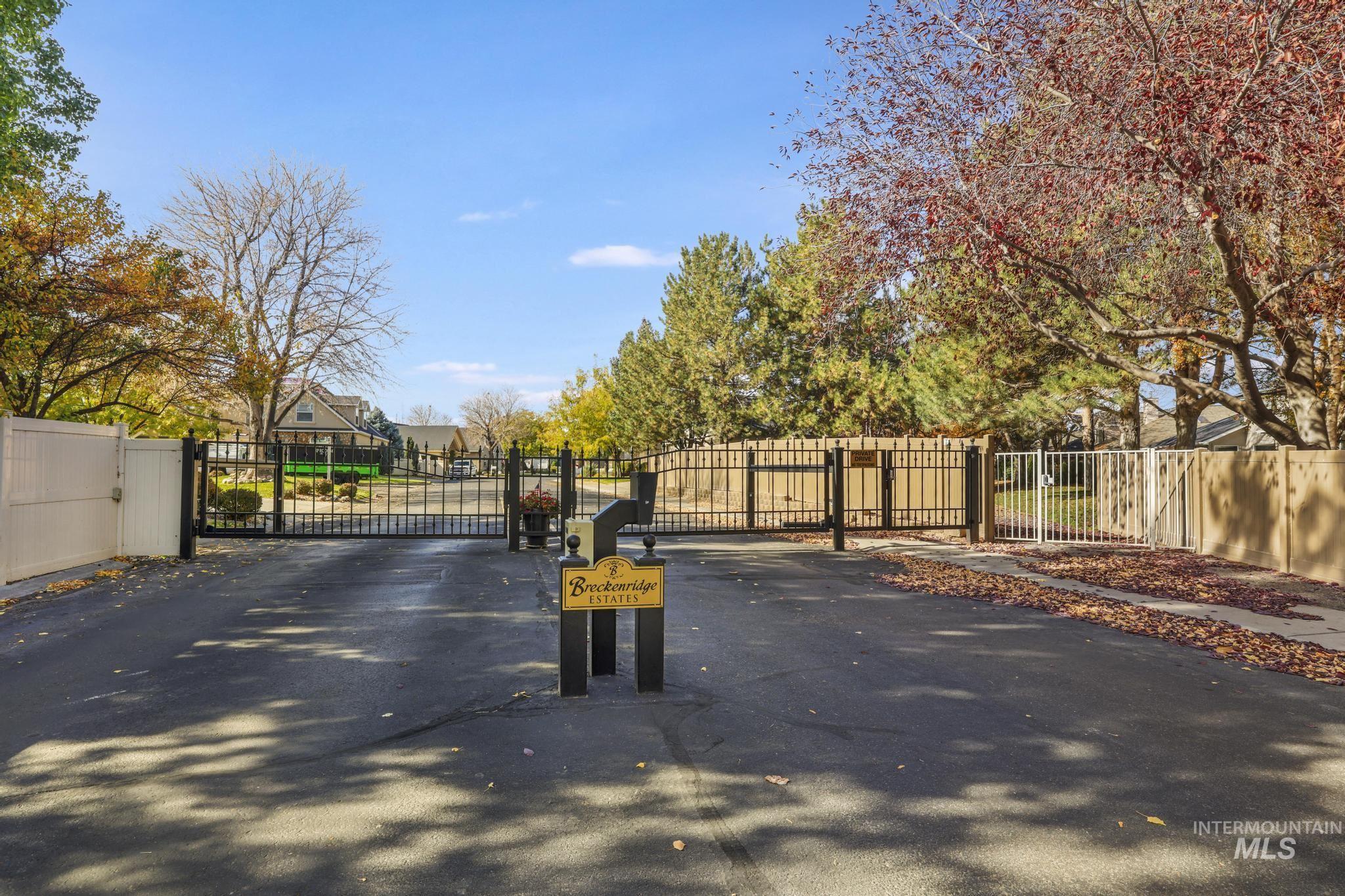 View of asphalt road featuring a gated entry, a gate, and curbs
