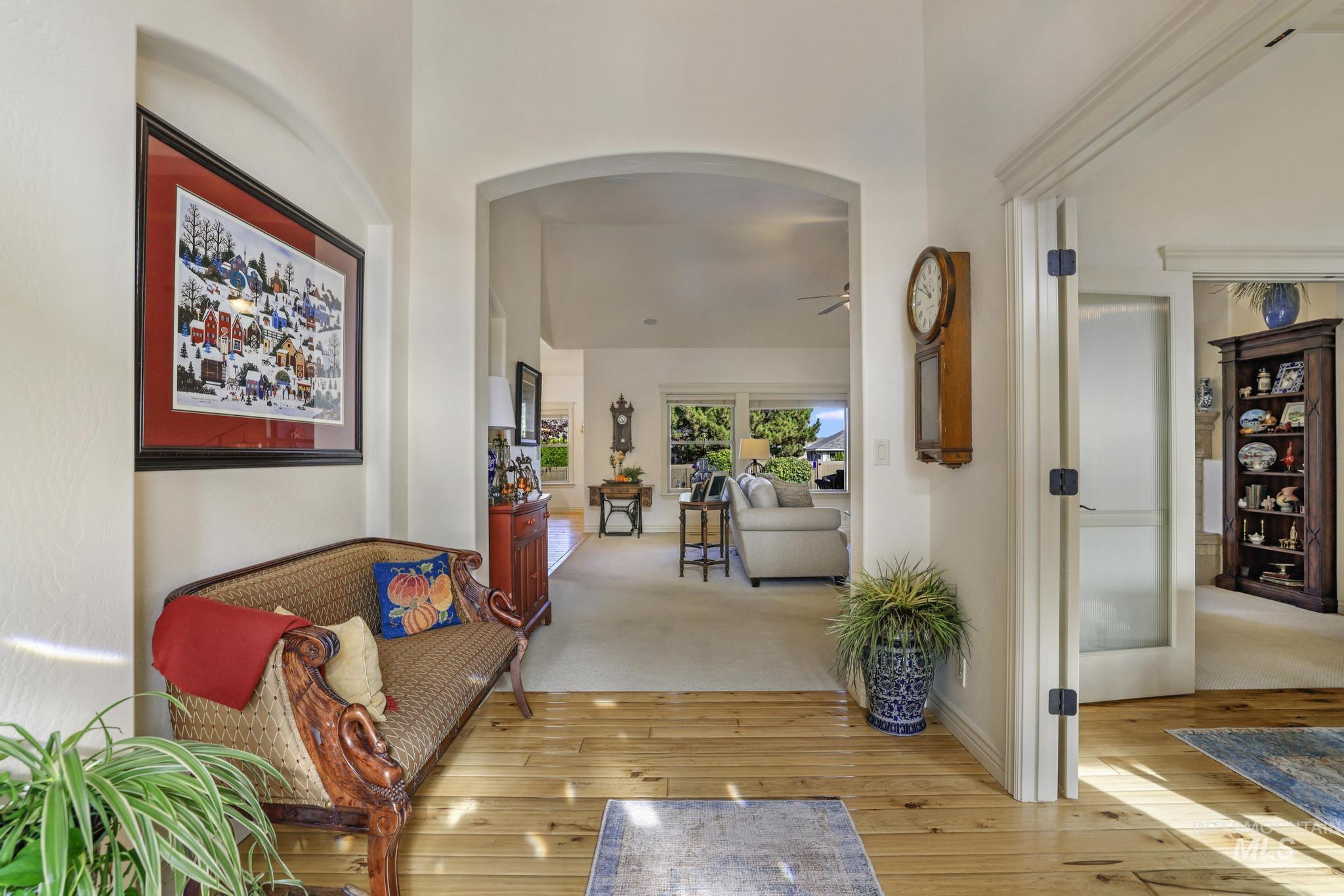 Hall featuring light wood-type flooring, arched walkways, a high ceiling, and light carpet