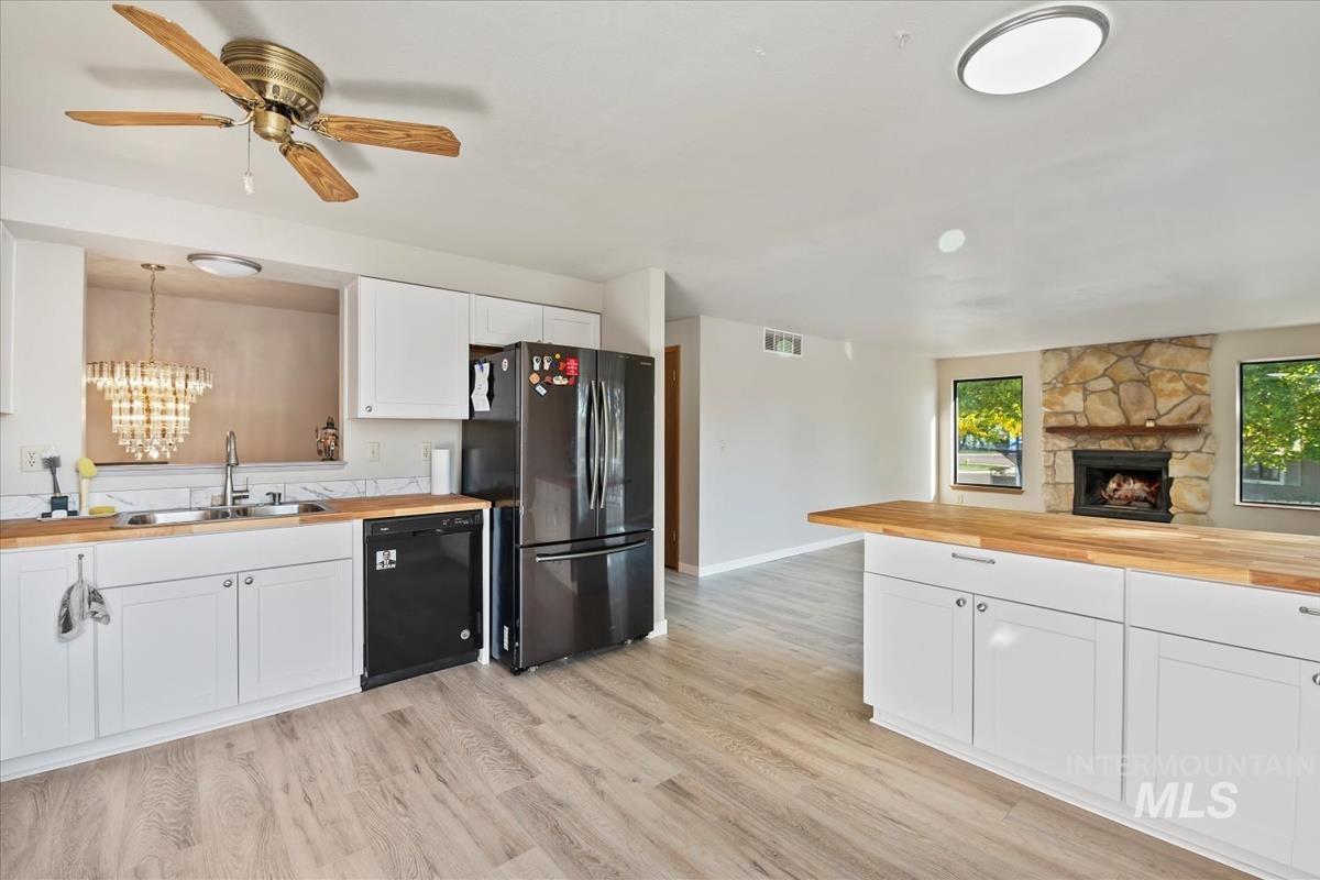 Kitchen featuring wood counters, white cabinets, freestanding refrigerator, and light wood-type flooring
